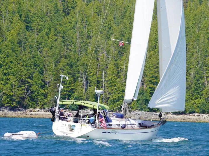 Slide: The Image of Sailing yacht Bavaria 49 (2003) cruising near a forested shoreline. - 0