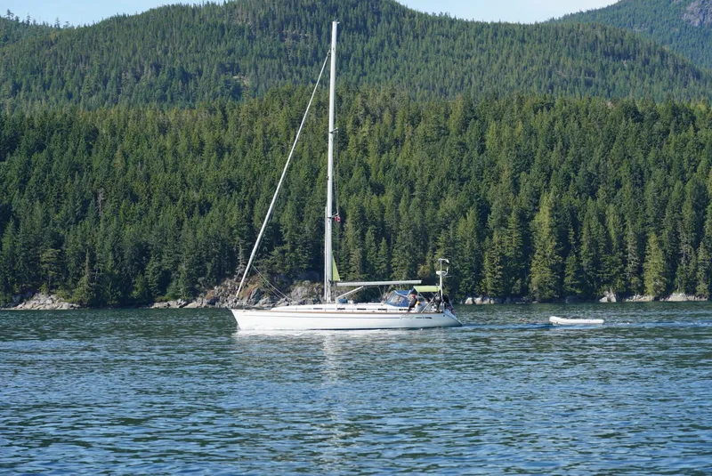 Slide: The Image of Sailboat Bavaria 49 (2003) cruising on a serene lake with forested hills in the background. - 1
