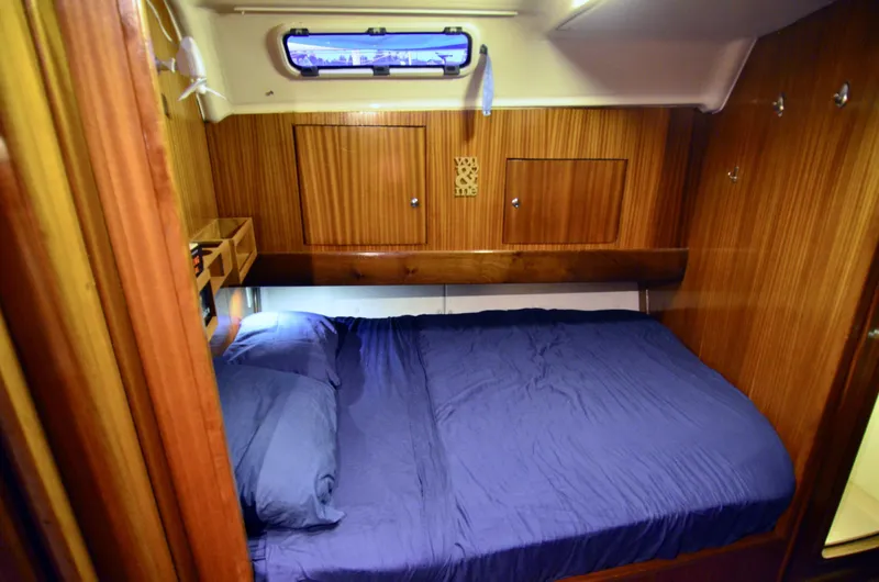 Slide: The Image of Cozy cabin interior of 2003 Bavaria 49 yacht with wooden paneling and blue bedding. - 11