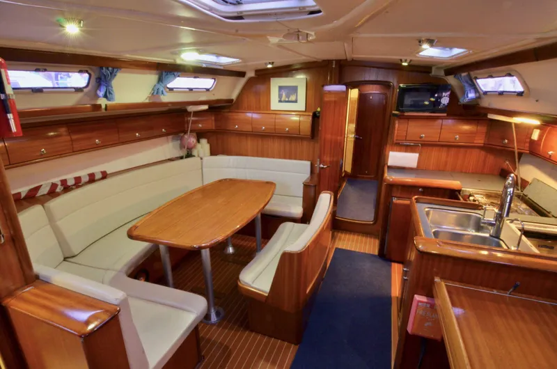 Slide: The Image of Interior of a 2003 Bavaria 49 yacht with wooden furnishings and a cozy dining area. - 2