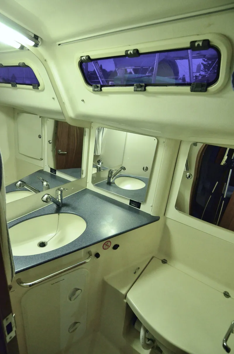 Slide: The Image of 2003 Bavaria 49 yacht bathroom with sink, mirror, and porthole window. - 20