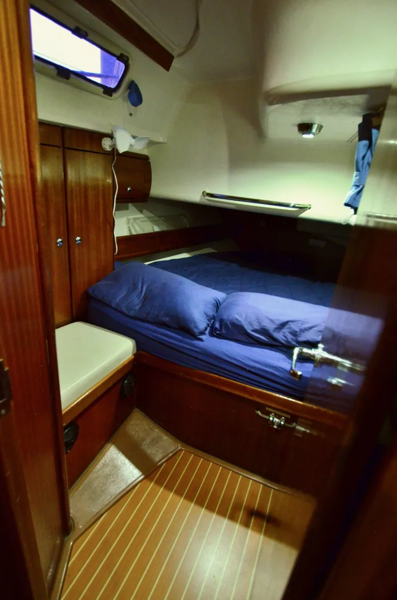 Slide: The Image of Cozy cabin interior of 2003 Bavaria 49 sailboat with wooden furnishings and blue bedding. - 21