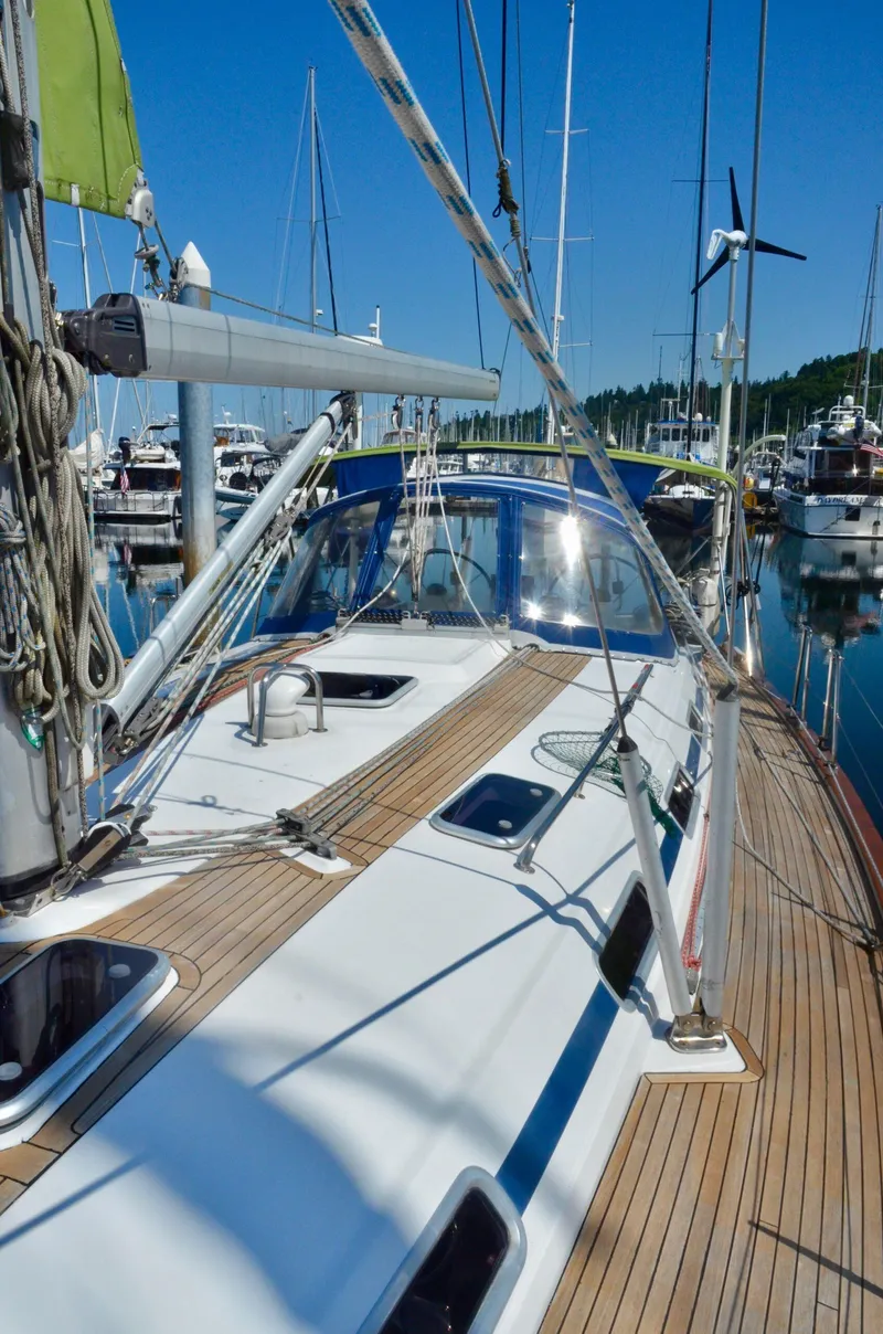 Slide: The Image of 2003 Bavaria 49 sailboat docked in a marina, showcasing its sleek deck and rigging. - 33