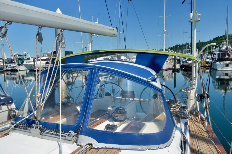 Slide: The Image of Bavaria 49 sailboat from 2003 docked in a marina, featuring a blue canopy. - 39