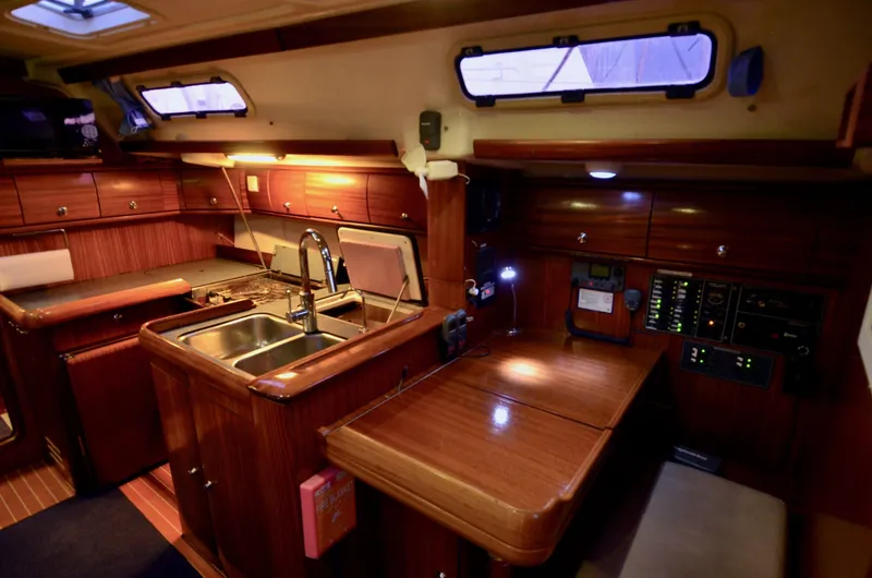 Slide: The Image of Luxurious 2003 Bavaria 49 yacht interior with wooden cabinetry and modern kitchen amenities. - 4