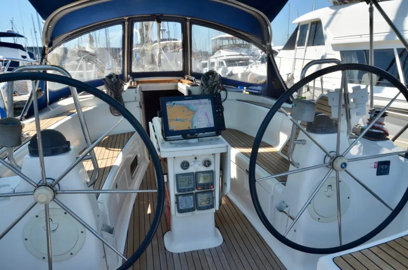 Slide: The Image of Cockpit of a 2003 Bavaria 49 sailboat with dual steering wheels and navigation equipment. - 46