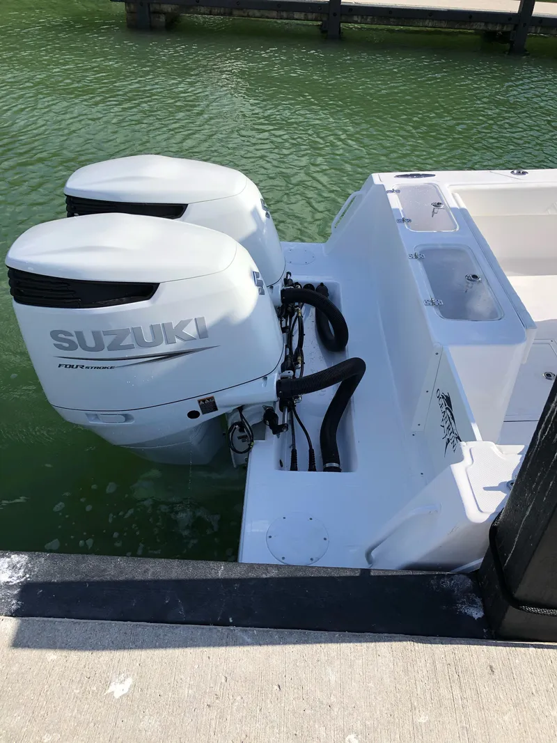Slide: The Image of Twin Suzuki outboard engines on a 2021 Ocean Runner 2900 CC boat docked in green water. - 18