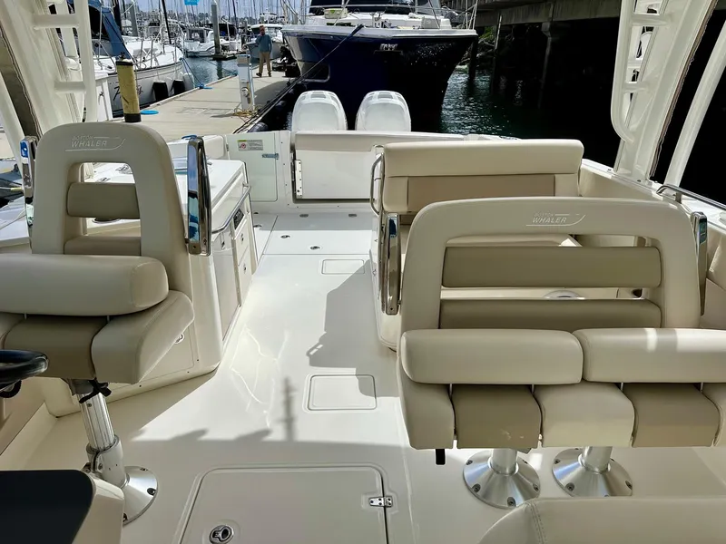 Slide: The Image of 2016 Boston Whaler 320 Vantage boat interior with beige seating at a marina. - 23