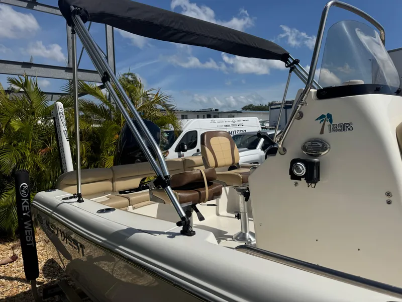 Slide: The Image of 2019 Key West 189 FS boat with canopy, beige seating, and tropical backdrop. - 11