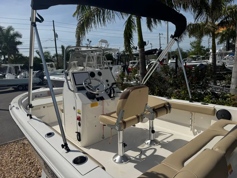 Slide: The Image of 2019 Key West 189 FS boat with canopy, parked outdoors near palm trees. - 19