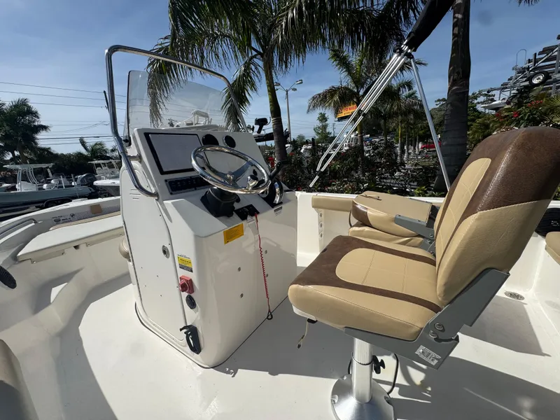 Slide: The Image of 2019 Key West 189 FS boat interior with steering console and seating under palm trees. - 22