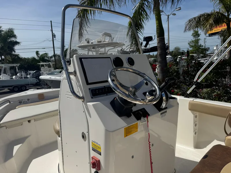 Slide: The Image of 2019 Key West 189 FS boat console with steering wheel and controls, surrounded by palm trees. - 23
