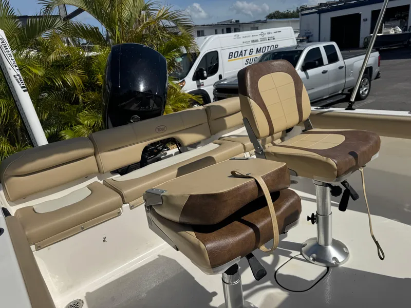 Slide: The Image of 2019 Key West 189 FS boat interior with tan seating and motor, parked near palm trees. - 36