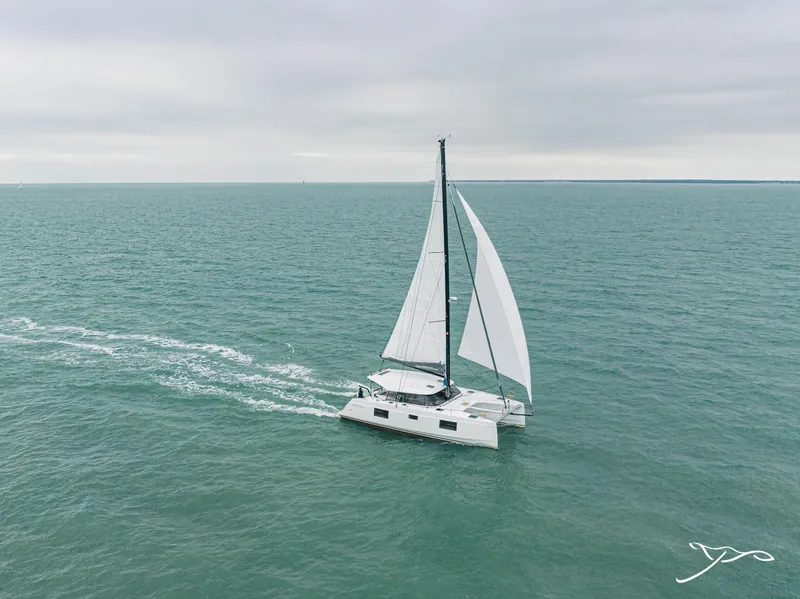 Slide: The Image of 2025 Nautitech 40 Open catamaran sailing on open sea under cloudy skies. - 0