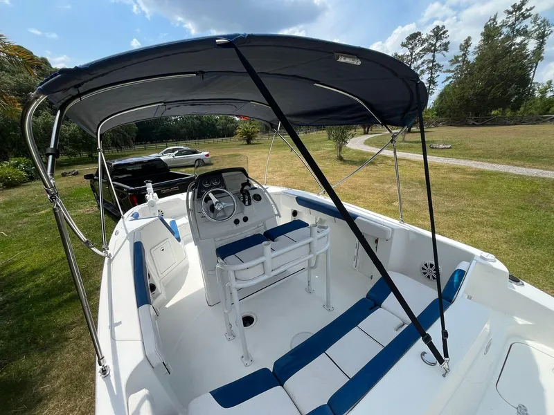 Slide: The Image of 2020 Tahoe 2150 CC boat with canopy, parked on grass under a blue sky. - 14