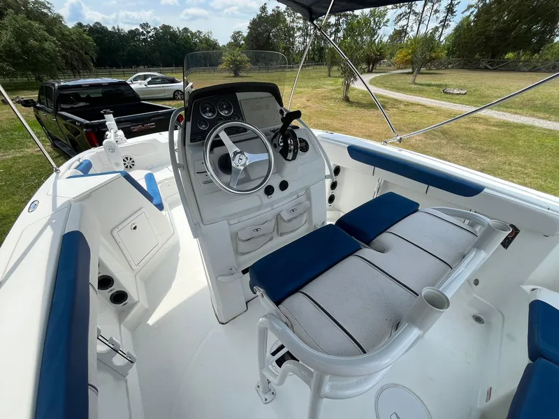 Slide: The Image of 2020 Tahoe 2150 CC boat interior with steering console and seating, parked outdoors. - 15