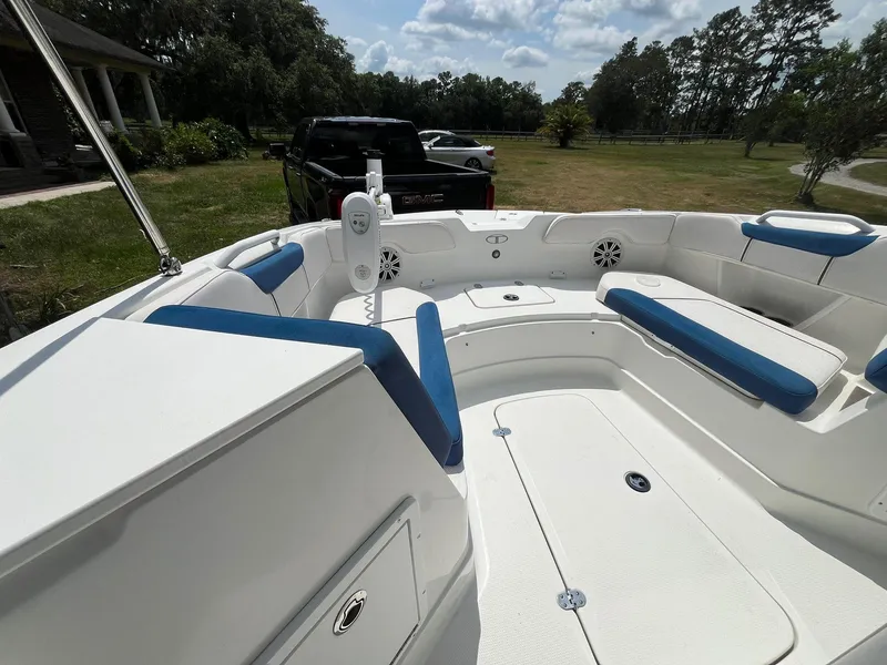 Slide: The Image of 2020 Tahoe 2150 CC boat interior with blue and white seating, parked outdoors. - 24