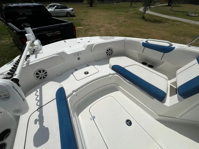 Slide: The Image of 2020 Tahoe 2150 CC boat interior with blue and white seating, parked outdoors. - 29