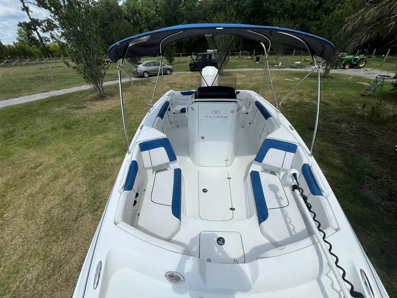 Slide: The Image of 2020 Tahoe 2150 CC boat with blue seating and canopy, parked on grass. - 33