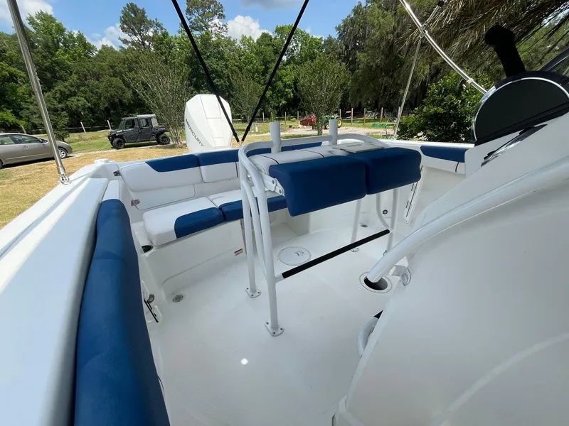 Slide: The Image of 2020 Tahoe 2150 CC boat interior with blue and white seating, surrounded by greenery. - 36
