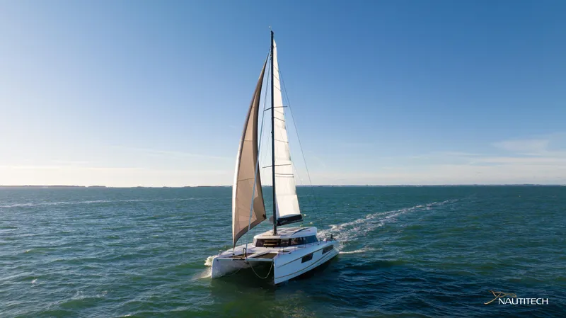 Slide: The Image of 2025 Nautitech 48 Open catamaran sailing on open sea under clear blue sky. - 1