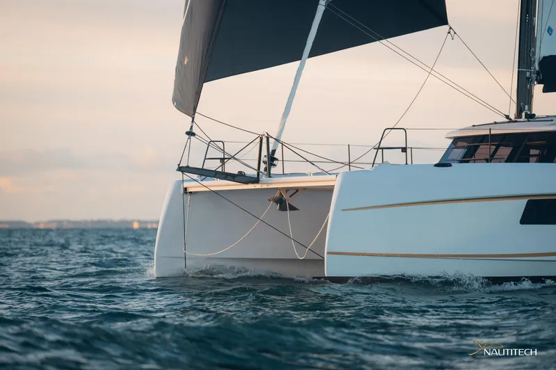 Slide: The Image of 2025 Nautitech 48 Open catamaran sailing on open water at sunset. - 6
