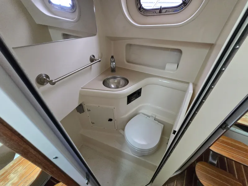 Slide: The Image of 2006 Pursuit 3370 Offshore boat bathroom with sink, toilet, and porthole window. - 15