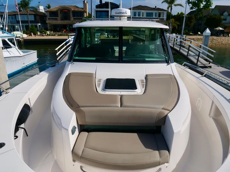 Slide: The Image of 2016 Tiara Yachts Q44 boat with cushioned seating, docked near waterfront homes. - 10