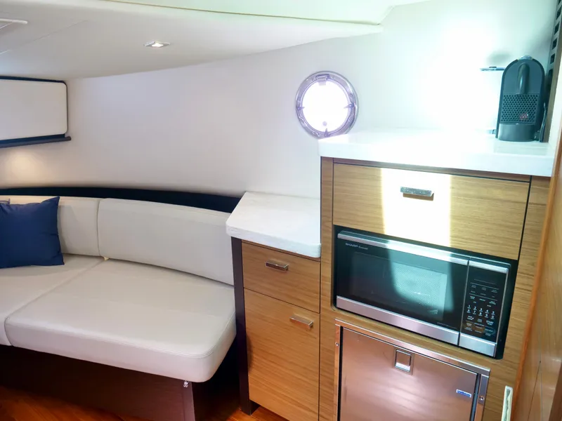 Slide: The Image of Interior of 2016 Tiara Yachts Q44 with sofa, microwave, and porthole. - 19