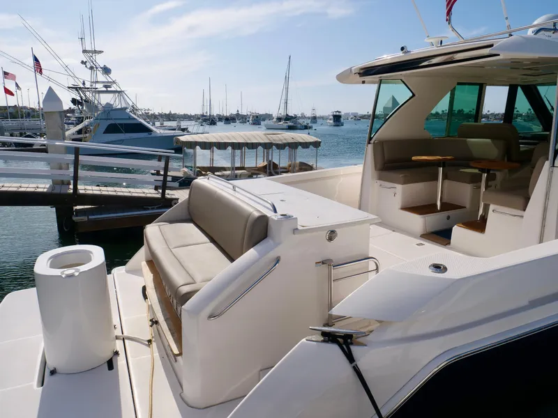 Slide: The Image of 2016 Tiara Yachts Q44 at marina, featuring spacious deck and seating area. - 5