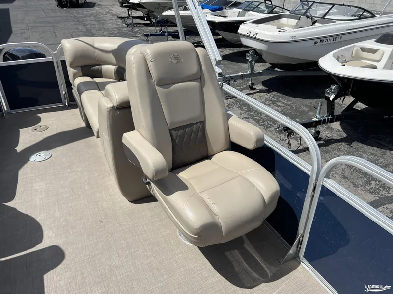 Slide: The Image of 2020 Sun Tracker Party Barge 24 DLX with beige seating, docked near other boats. - 6