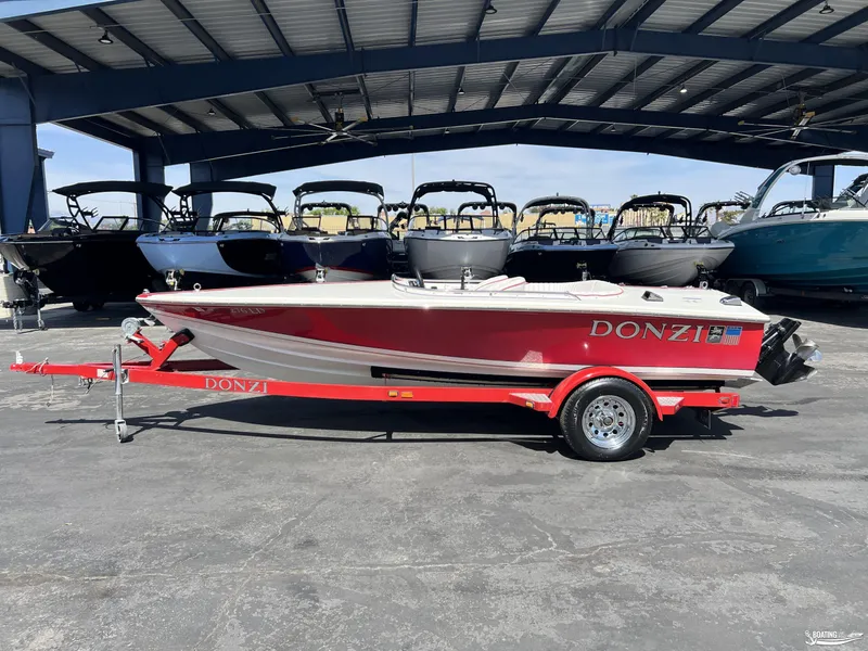 Slide: The Image of 1996 Donzi Sweet 16 boat in red on a matching trailer, parked under a metal canopy. - 0