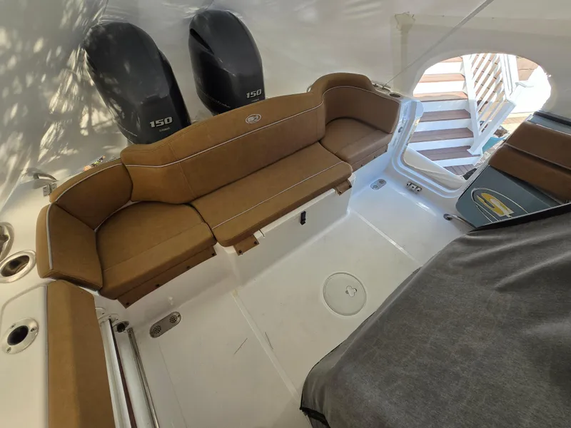Slide: The Image of 2023 Sea Hunt Ultra 265 SE boat interior with brown seating and dual 150 engines. - 11