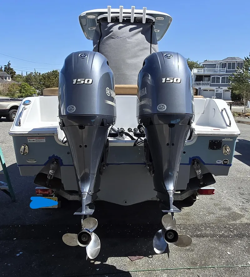 Slide: The Image of 2023 Sea Hunt Ultra 265 SE boat with dual Yamaha 150 engines, parked outdoors. - 32