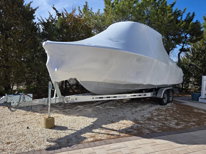Slide: The Image of 2023 Sea Hunt Ultra 265 SE boat covered on a trailer, parked outdoors. - 34