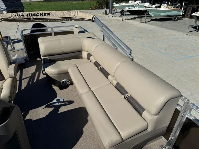 Slide: The Image of 2025 Sun Tracker 24 Sportfish XP3 pontoon boat interior with beige seating and steering console. - 14