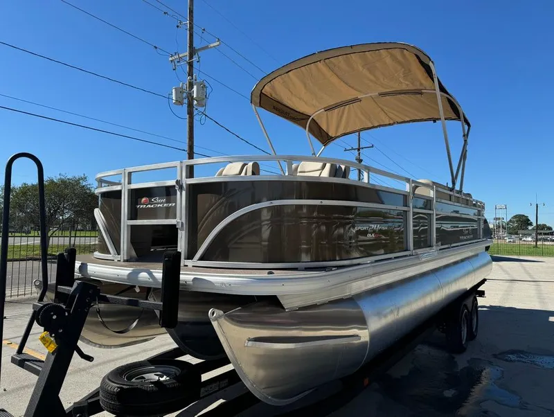 Slide: The Image of 2025 Sun Tracker 24 Sportfish XP3 pontoon boat on trailer, parked outdoors. - 2