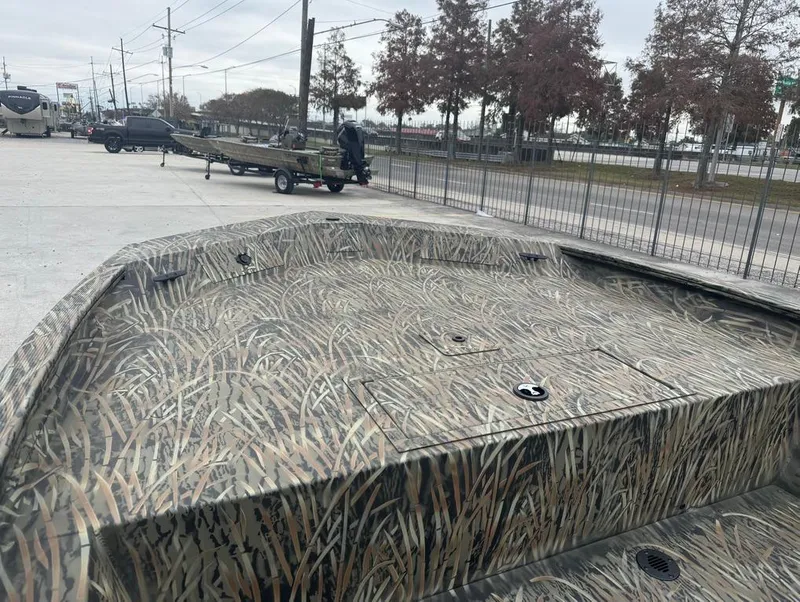 Slide: The Image of 2025 Tracker 1860 Grizzly boat with camouflage design parked outdoors. - 11