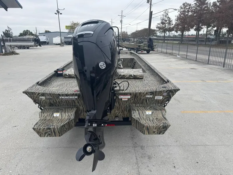 Slide: The Image of 2025 Tracker 1860 Grizzly boat with outboard motor, parked outdoors. - 6