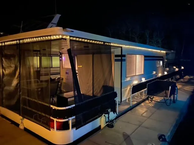Slide: The Image of 1976 Sumerset 12x55 houseboat illuminated at night, docked with visible deck and seating area. - 0