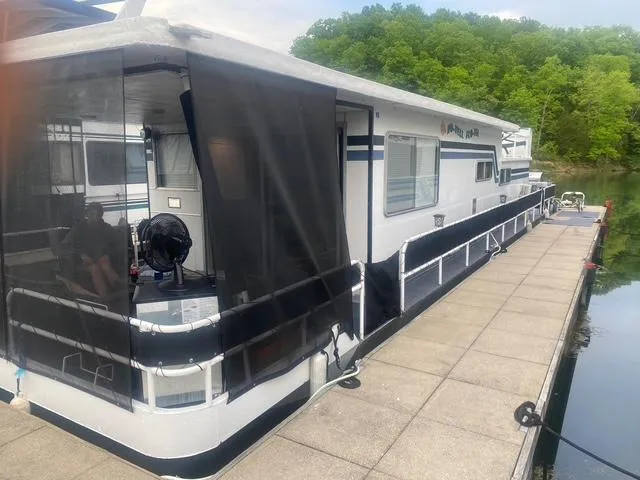Slide: The Image of 1976 Sumerset 12x55 houseboat docked on a calm lake with lush greenery. - 1