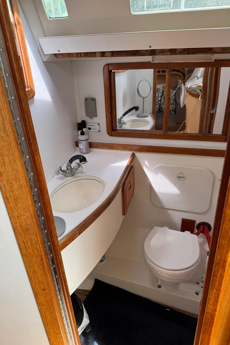 Slide: The Image of 1993 Catalina 42 yacht bathroom with sink, mirror, and toilet, featuring wood accents. - 21