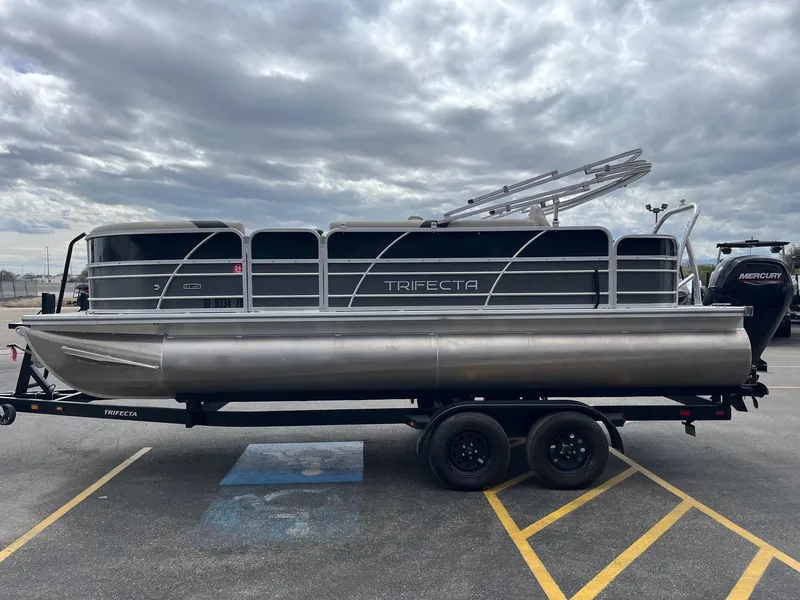 Slide: The Image of 2022 Trifecta 22 LE Rear Fish pontoon boat on trailer under cloudy sky. - 7