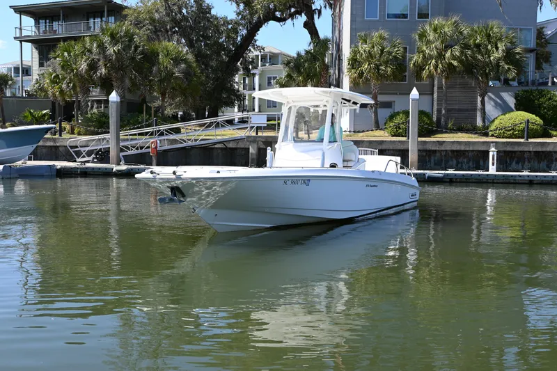 Slide: The Image of 2014 Boston Whaler 270 Dauntless boat docked in a serene marina setting. - 1