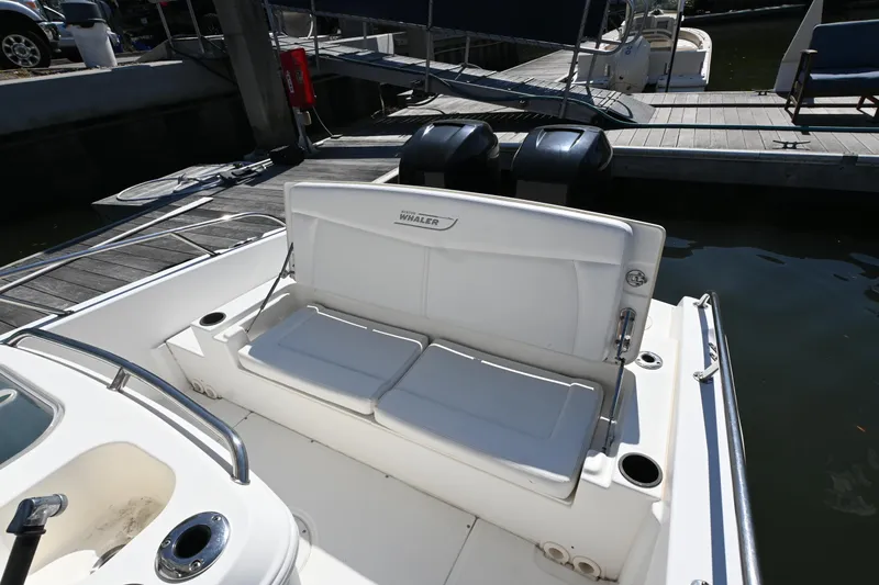 Slide: The Image of 2014 Boston Whaler 270 Dauntless boat with cushioned seating at dock. - 14
