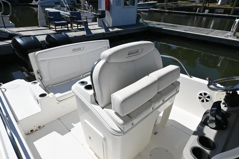 Slide: The Image of 2014 Boston Whaler 270 Dauntless boat interior with seating and console at dock. - 7