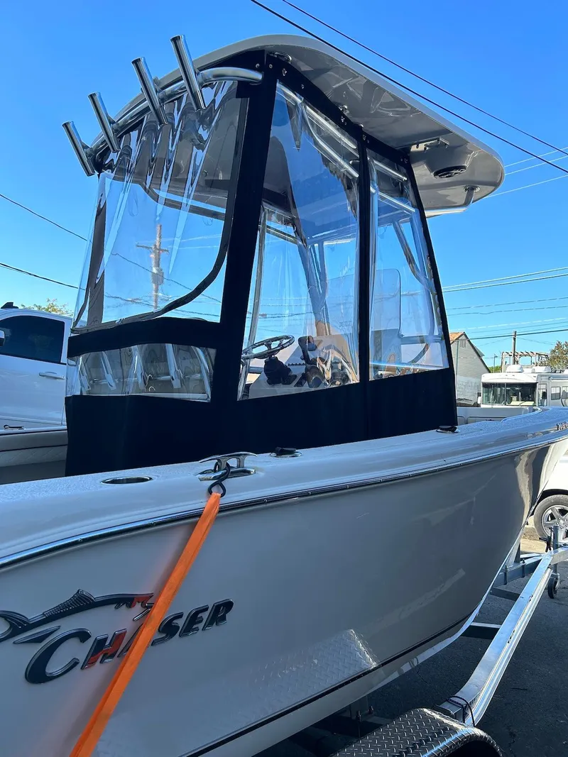 Slide: The Image of 2022 Sea Chaser 20 HFC boat with clear enclosure and rod holders, parked on a trailer. - 3