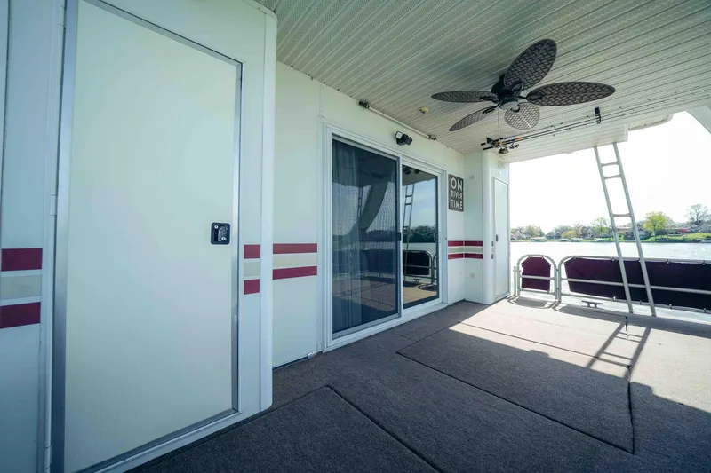 Slide: The Image of 1999 Sumerset houseboat deck with sliding doors, ceiling fan, and outdoor seating. - 12