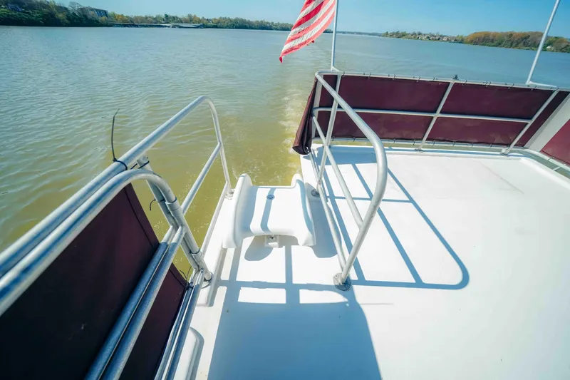 Slide: The Image of 1999 Sumerset houseboat deck with railing and American flag on a calm river. - 14