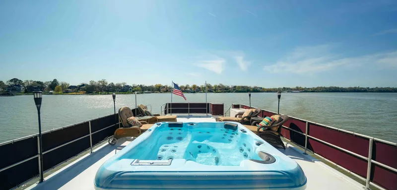 Slide: The Image of Sumerset 1999 houseboat with jacuzzi on deck, overlooking serene lake and clear blue sky. - 17